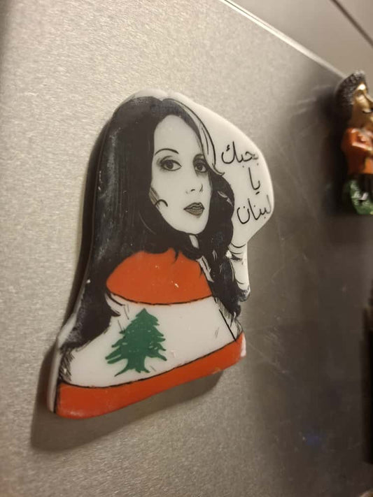 Fridge magnet with a stylized portrait and Lebanese flag design on a metallic surface.