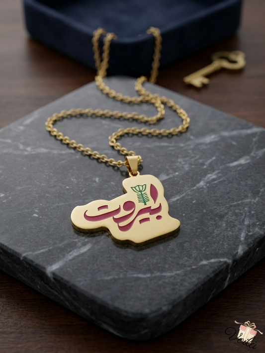 Gold-plated Lebanon map necklace featuring Beirut Arabic calligraphy on a marble display