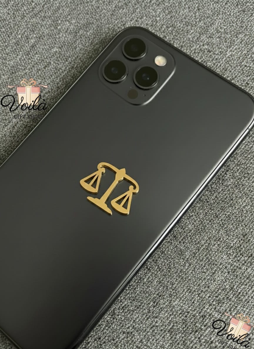 Black phone case with gold Libra zodiac symbol on a gray textured surface