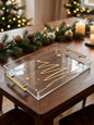 Clear acrylic holiday tray with golden Christmas tree design and gold handles on wooden table