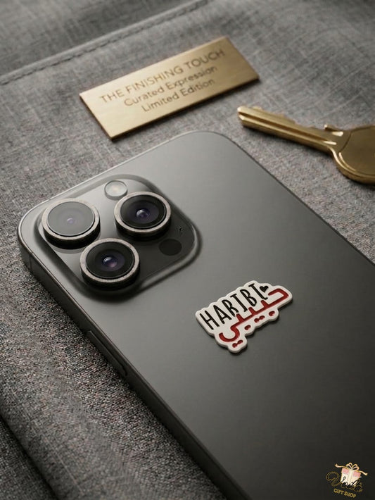 Smartphone with a habibi sticker on a textured surface with a key and nameplate.