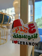 Fridge magnet with Lebanese text and flag colors on a surface