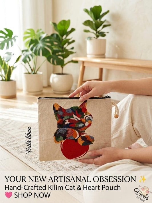 Woman sitting in a sunny room holding a premium hand-crafted kilim tapestry pouch featuring a colorful woven cat resting on a large red heart.
