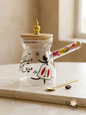 Hand-painted glass Lebanese Rakweh coffee pot with dried flowers in the handle and a gold spoon.