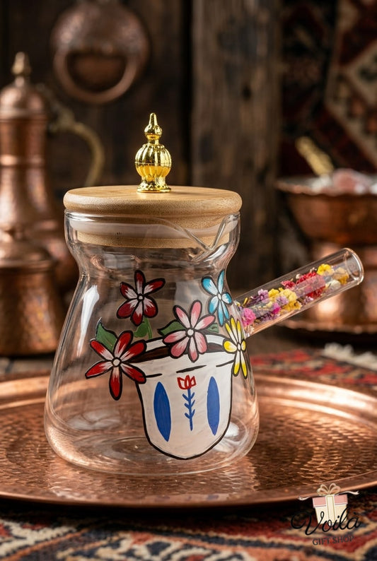 Hand-painted glass rakweh with a bamboo lid and dried flower handle on a copper tray