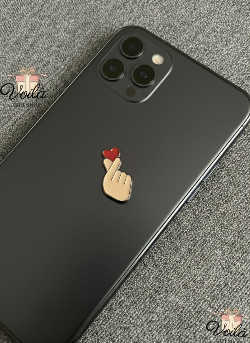 Phone case with a hand and heart design on a gray surface, branded 'Voila'.
