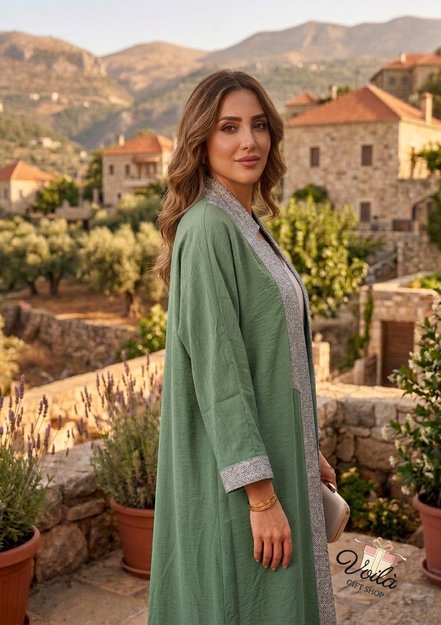 Elegant sage green abaya with textured silver trim worn in a traditional Lebanese village