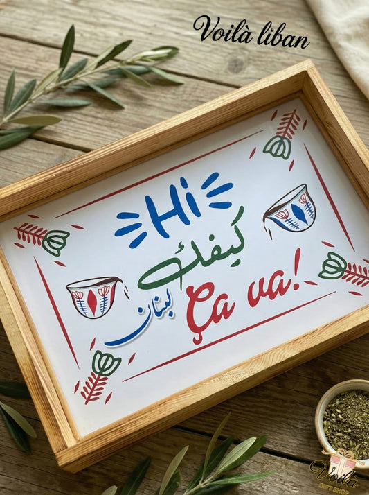 Wooden tray with a colorful message in French on a wooden surface with olive branches.