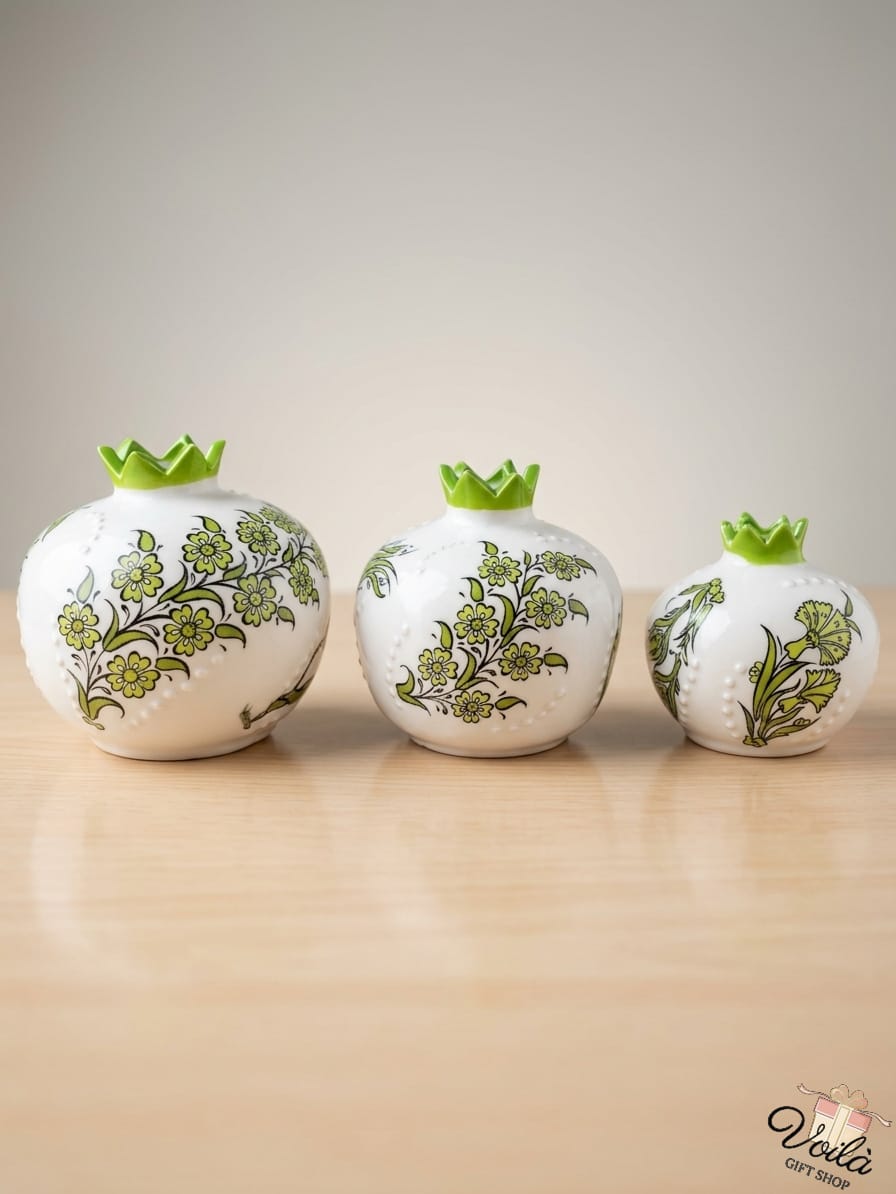 Set of three premium ceramic pomegranate vases in cascading sizes, featuring delicate hand-painted green traditional Iznik floral patterns with a glazed green scalloped crown, resting gracefully on a light wood surface.