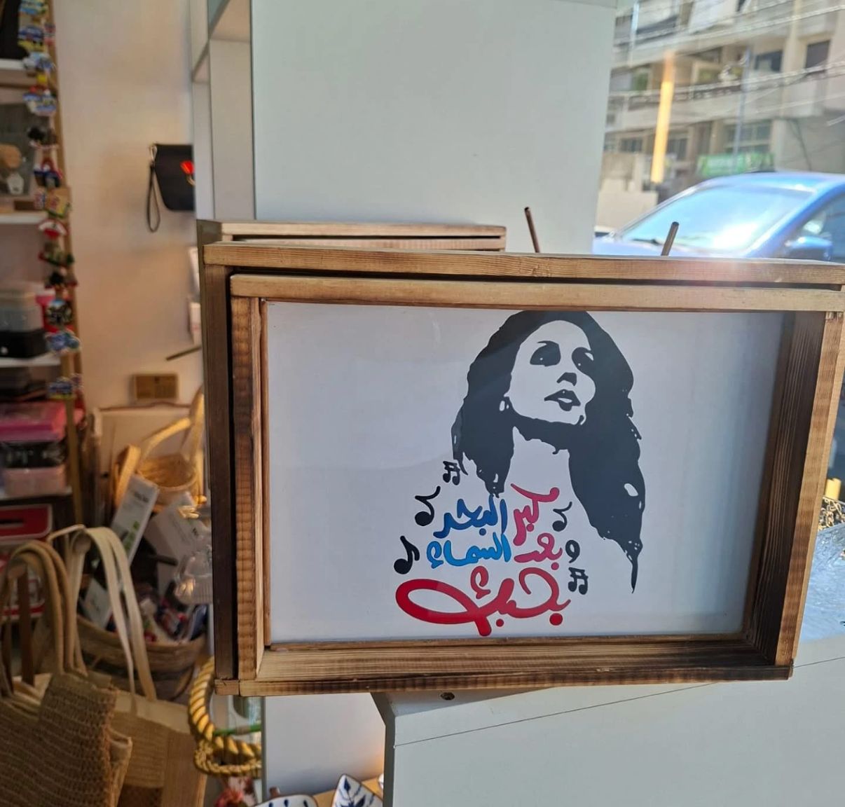 Framed artwork with a stylized portrait and Arabic text on a stand in a store setting.