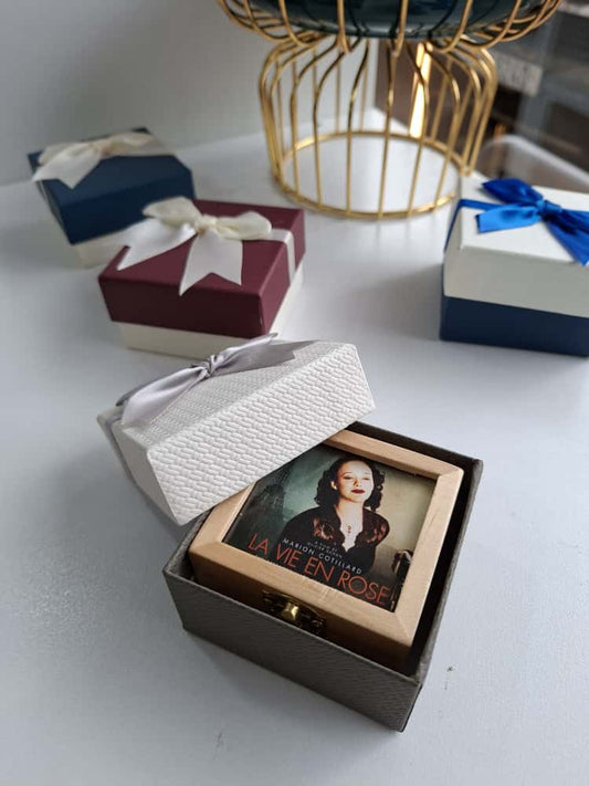Open gift box with a photo inside, surrounded by other gift boxes on a white surface.