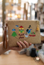 Handcrafted embroidered jute clutch with Lebanese heritage symbols and leather strap