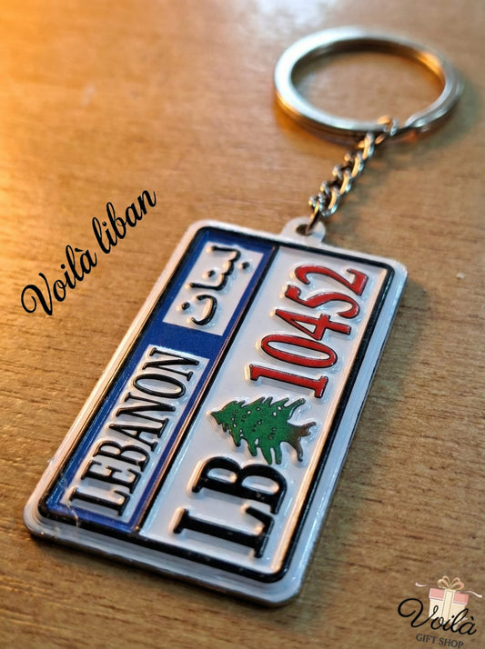 Keychain designed like a Lebanese license plate on a wooden surface