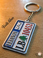 Keychain designed like a Lebanese license plate on a wooden surface