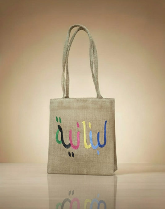 Jute bag with colorful Arabic text on a beige background