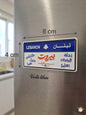 Decorative Lebanese license plate fridge magnet measuring 8cm by 4cm, featuring the names of iconic cities in Arabic calligraphy including Beirut in bold red, surrounded by Tripoli, Byblos, Sidon, Zahle, Batroun, and Baalbek.