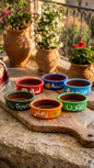 Six colorful hand-painted Lebanese clay mezze bowls on a wooden board