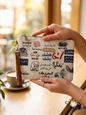 Hands holding a canvas pouch featuring funny Arabic pop culture memes and a brown wristlet strap