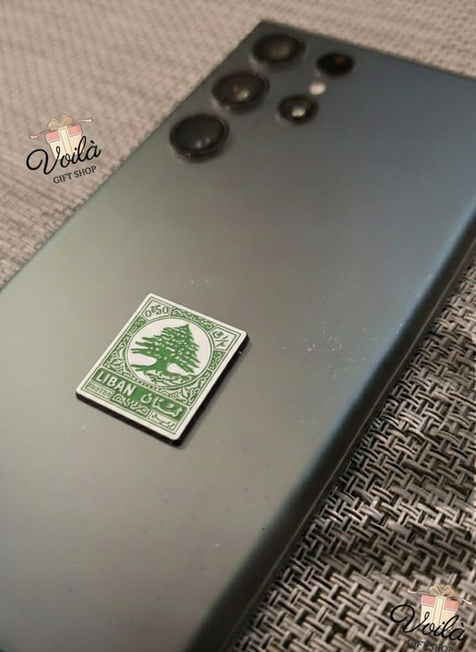 Phone case with a green and white sticker featuring a tree design on a textured surface.