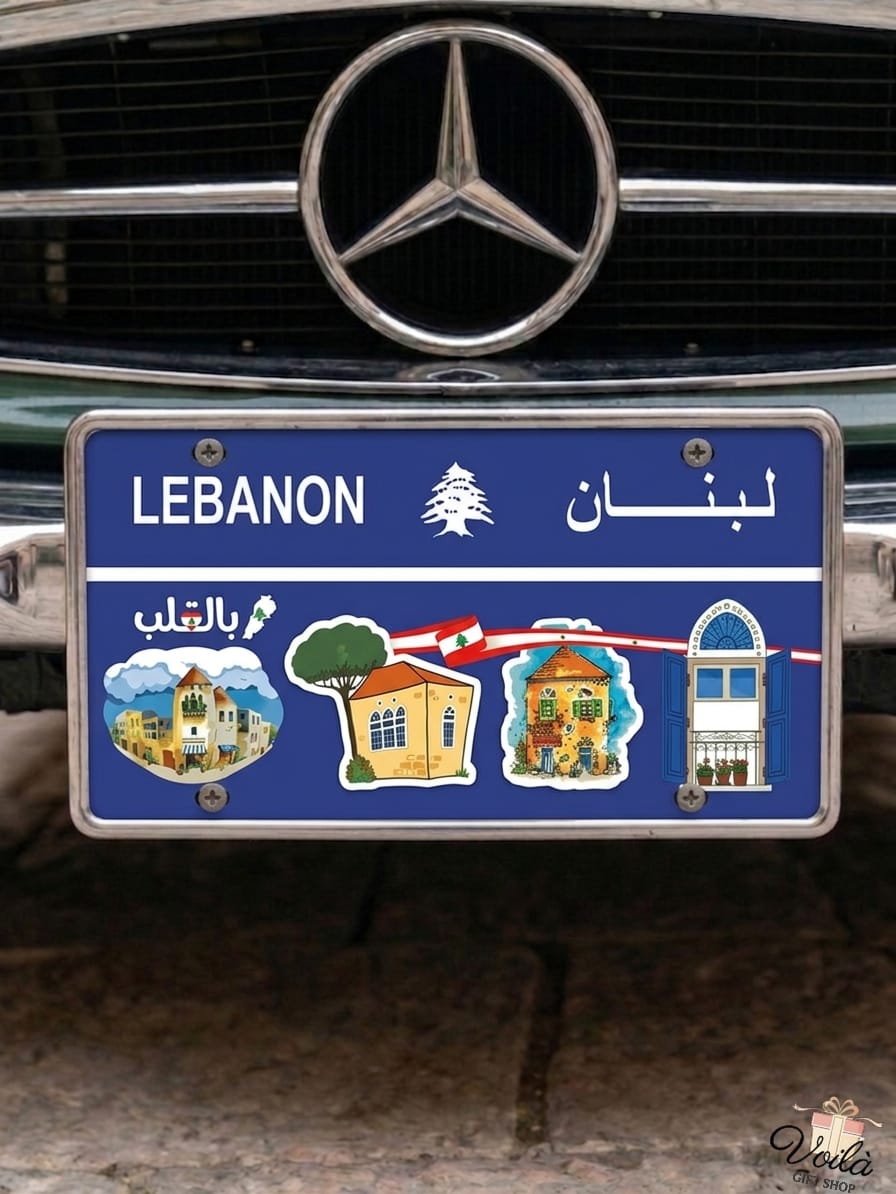 Blue decorative Lebanese license plate mounted on a classic car, featuring illustrations of traditional village houses with red tile roofs, iconic triple-arched windows, the Lebanese flag, and Arabic text reading Bil Qaleb.