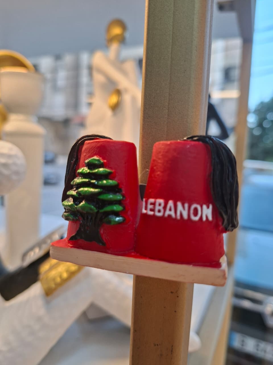 Red earrings with a green tree design and 'Lebanon' text on a stand.