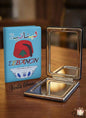 Compact mirror and blue notebook with Lebanese design on a wooden surface