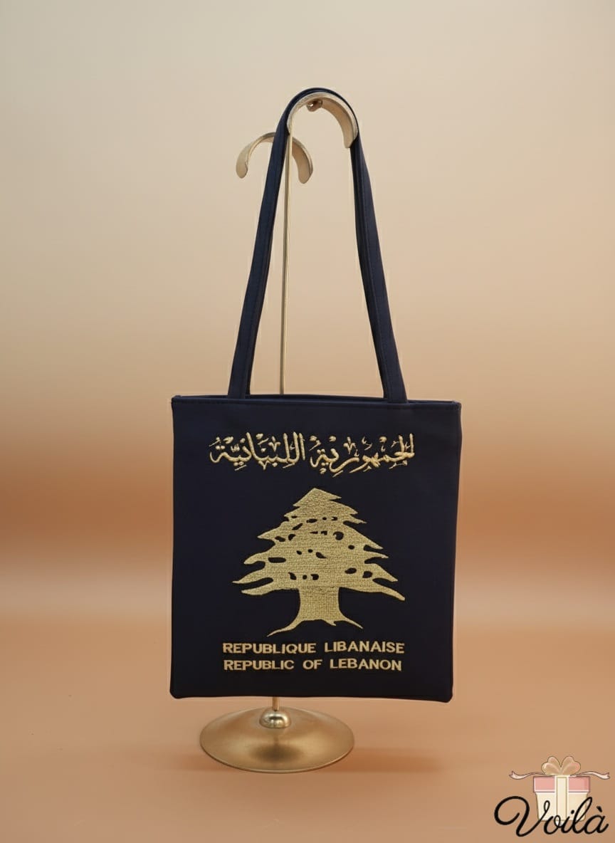 Black tote bag with gold tree design and text on a stand against a beige background