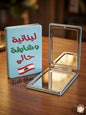 Compact mirror with Lebanese flag and text on a wooden surface