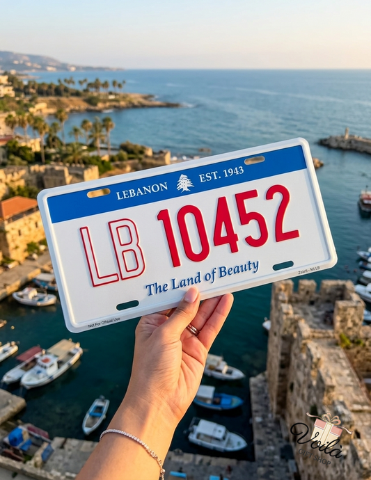 Hand holding a decorative Lebanon license plate with LB 10452 and The Land of Beauty text over Byblos harbor
