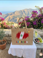 Handcrafted jute tote bag featuring the Lebanese flag and colorful Lebanon text set against a scenic mountain backdrop