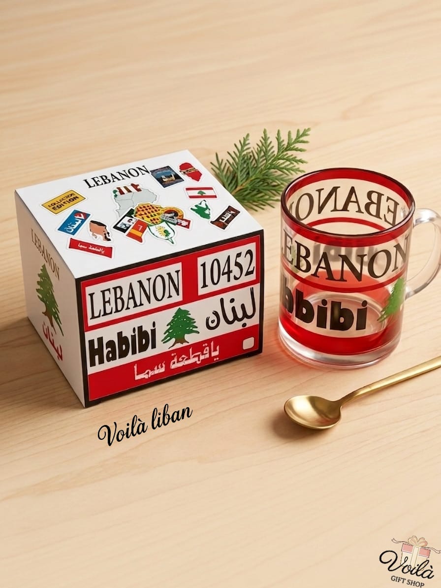 Glass mug with 'Lebanon' text on a wooden surface next to a box labeled 'Lebanon'.