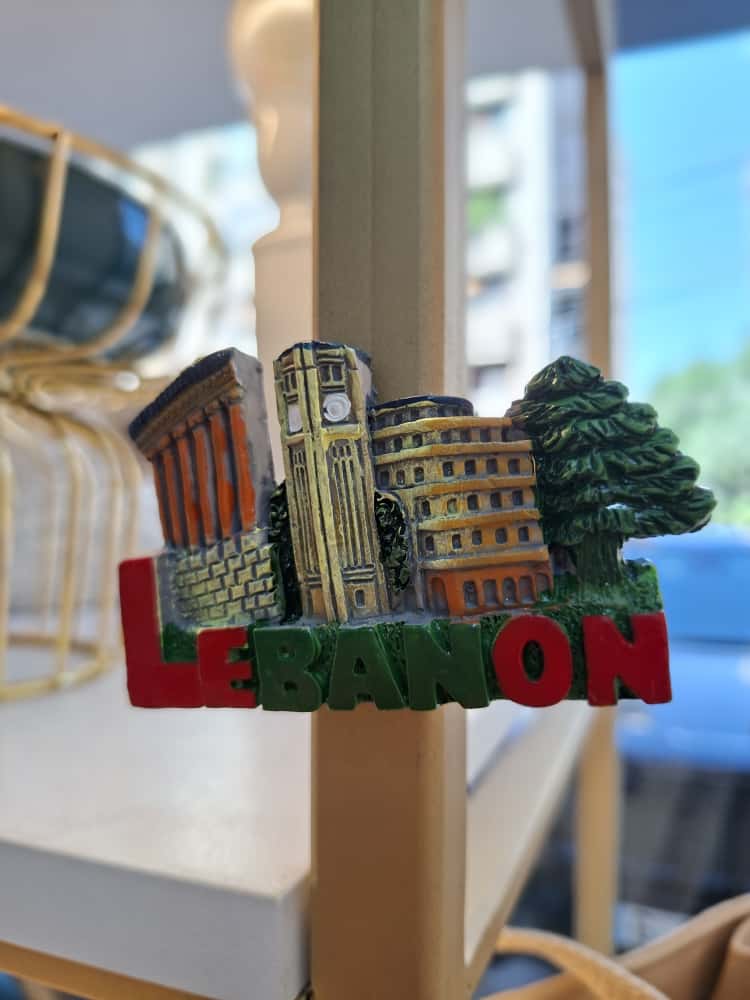 Fridge magnet with architectural design and 'Lebanon' text on a blurred background