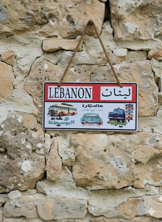 Decorative sign with 'Lébanon' text and vintage bus illustrations on a stone wall background.