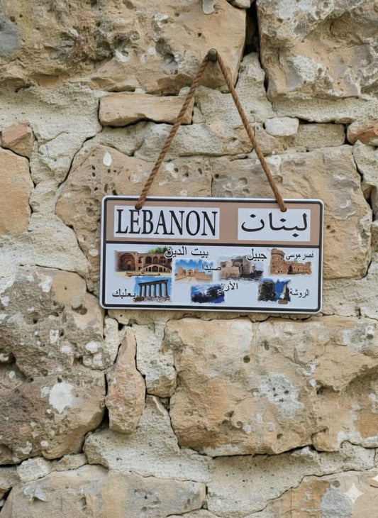 Decorative sign with 'LEBANON' text and images of landmarks on a stone wall.