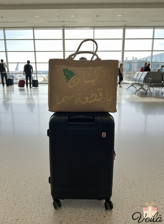 Beige bag with Arabic text on top of a black suitcase in an airport terminal.