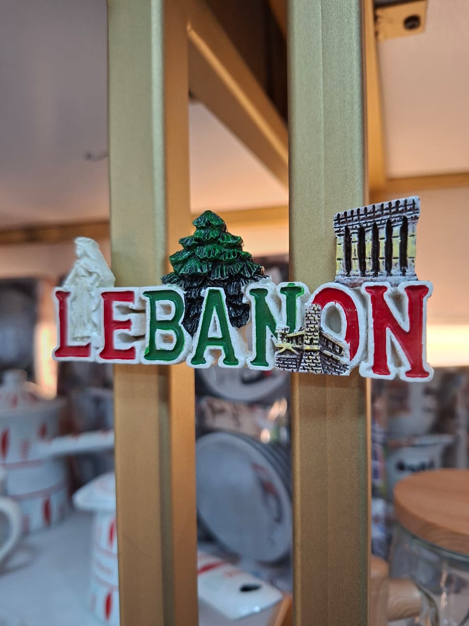 Fridge magnet with 'LEBANON' text and symbols on a wooden surface.