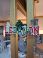 Fridge magnet with 'LEBANON' text and symbols on a wooden surface.