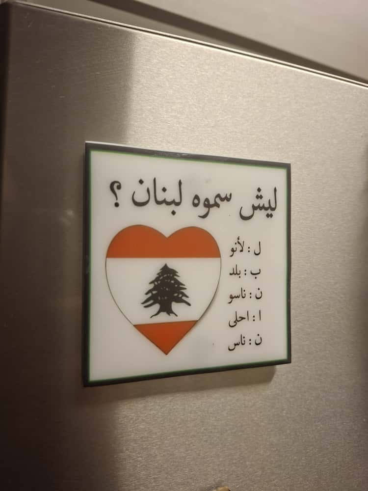 Heart-shaped sign with Lebanese flag design and Arabic text on a metallic surface