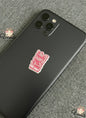 Black smartphone with a pink sticker on a gray textured surface