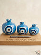 et of three premium light blue ceramic pomegranate vases in cascading sizes, featuring a striking traditional concentric circle motif, displayed elegantly on a wooden board.