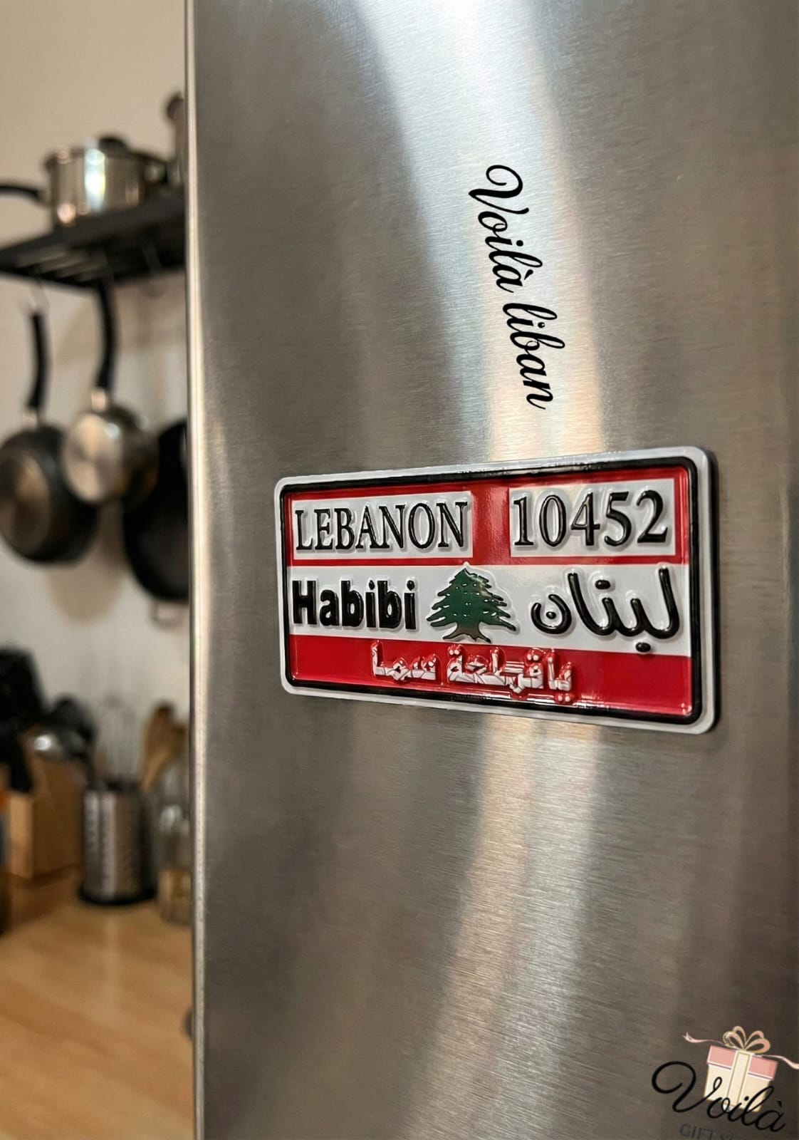 Metallic surface with a Lebanese license plate-style magnet and 'Vela Liban' branding.