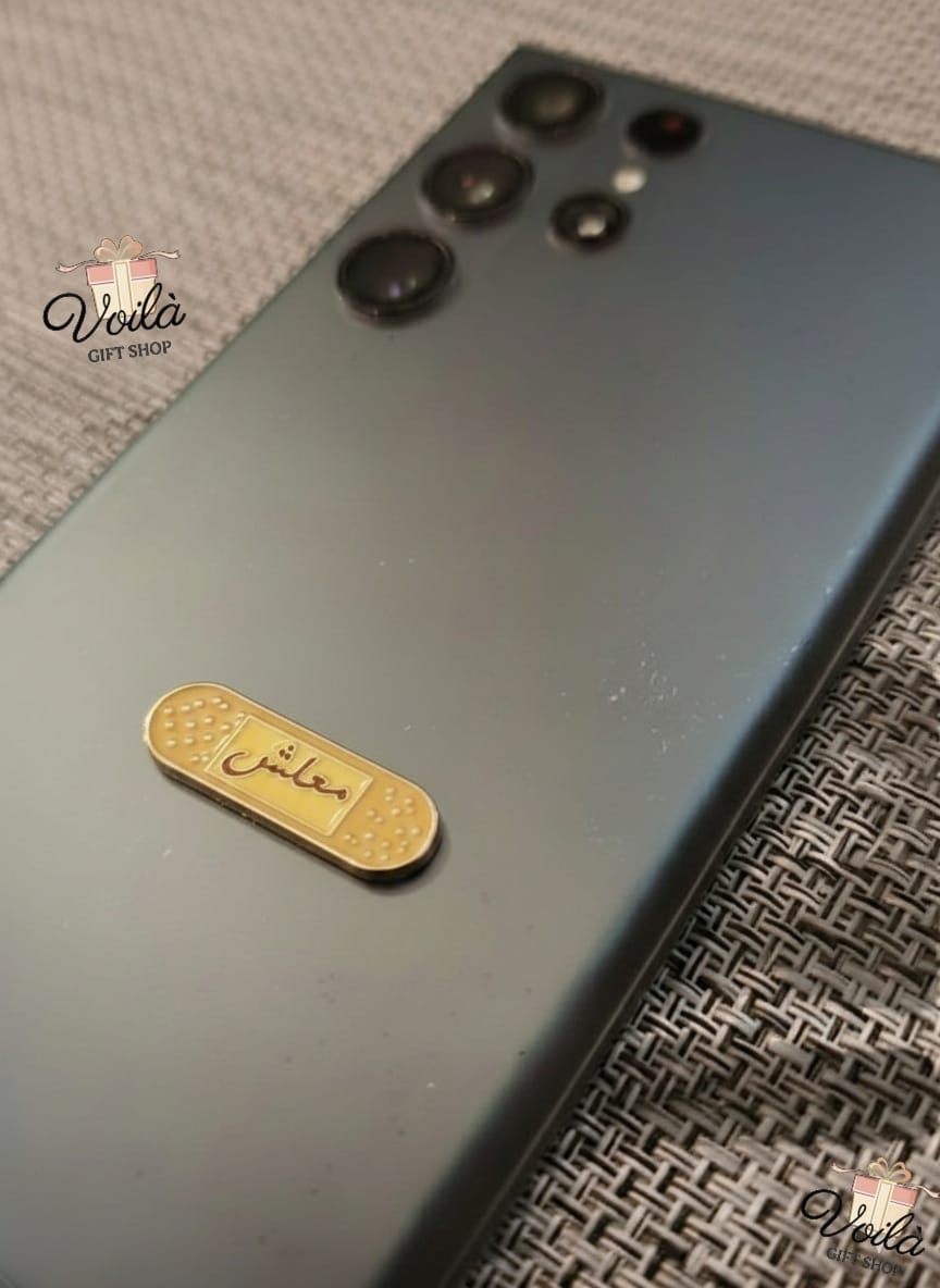 Smartphone with a gold badge on a textured surface, branded 'Voila'.