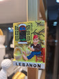Decorative magnet with a man sitting on a chair, holding a basket, and a window in the background, labeled 'Lebanon'.