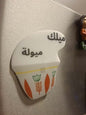 Fridge magnet shaped like a milk carton with Arabic text on a refrigerator.