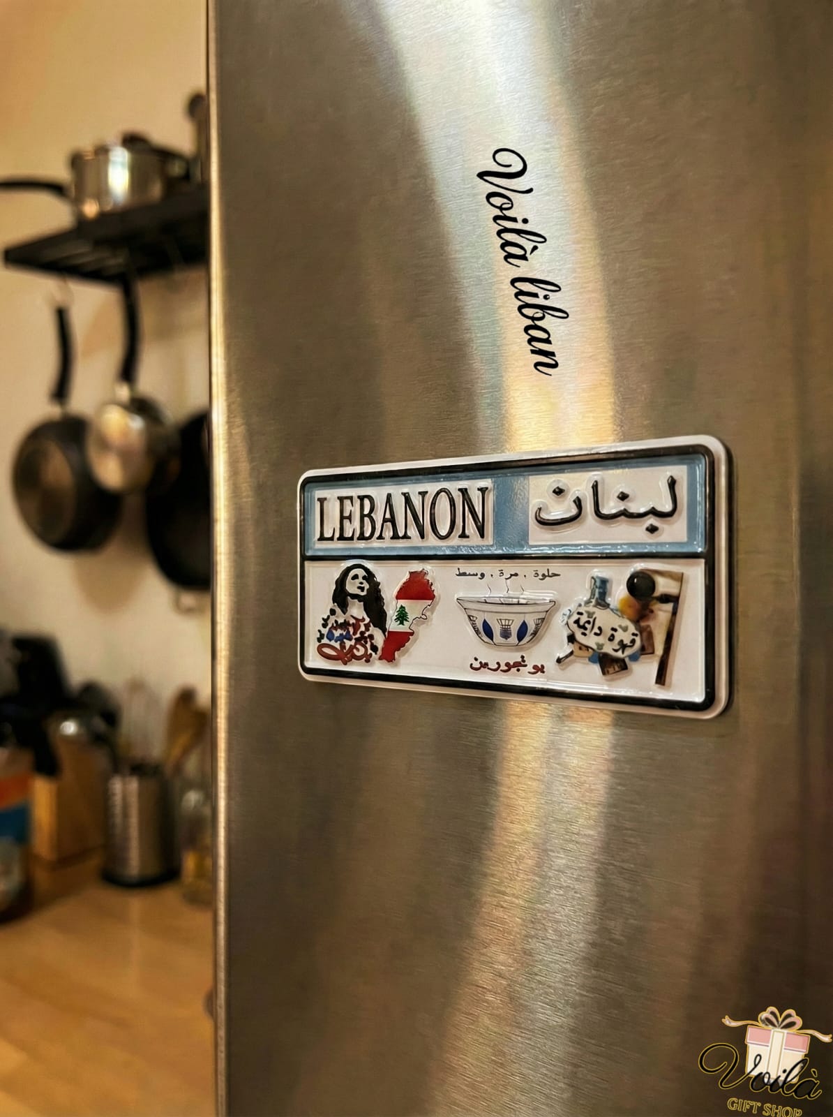 Stainless steel refrigerator with a 'Lebanon' themed magnet on a kitchen background