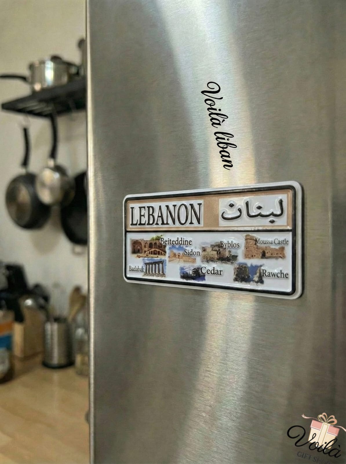 Fridge with a 'Lebanon' themed magnet featuring images and text on a kitchen background.