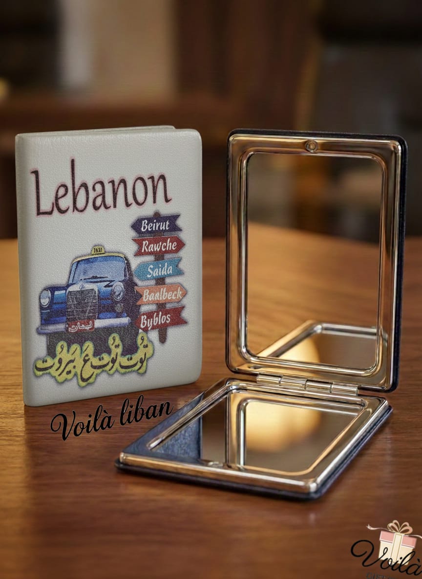 Compact mirror with a case featuring a car illustration and text on a wooden surface