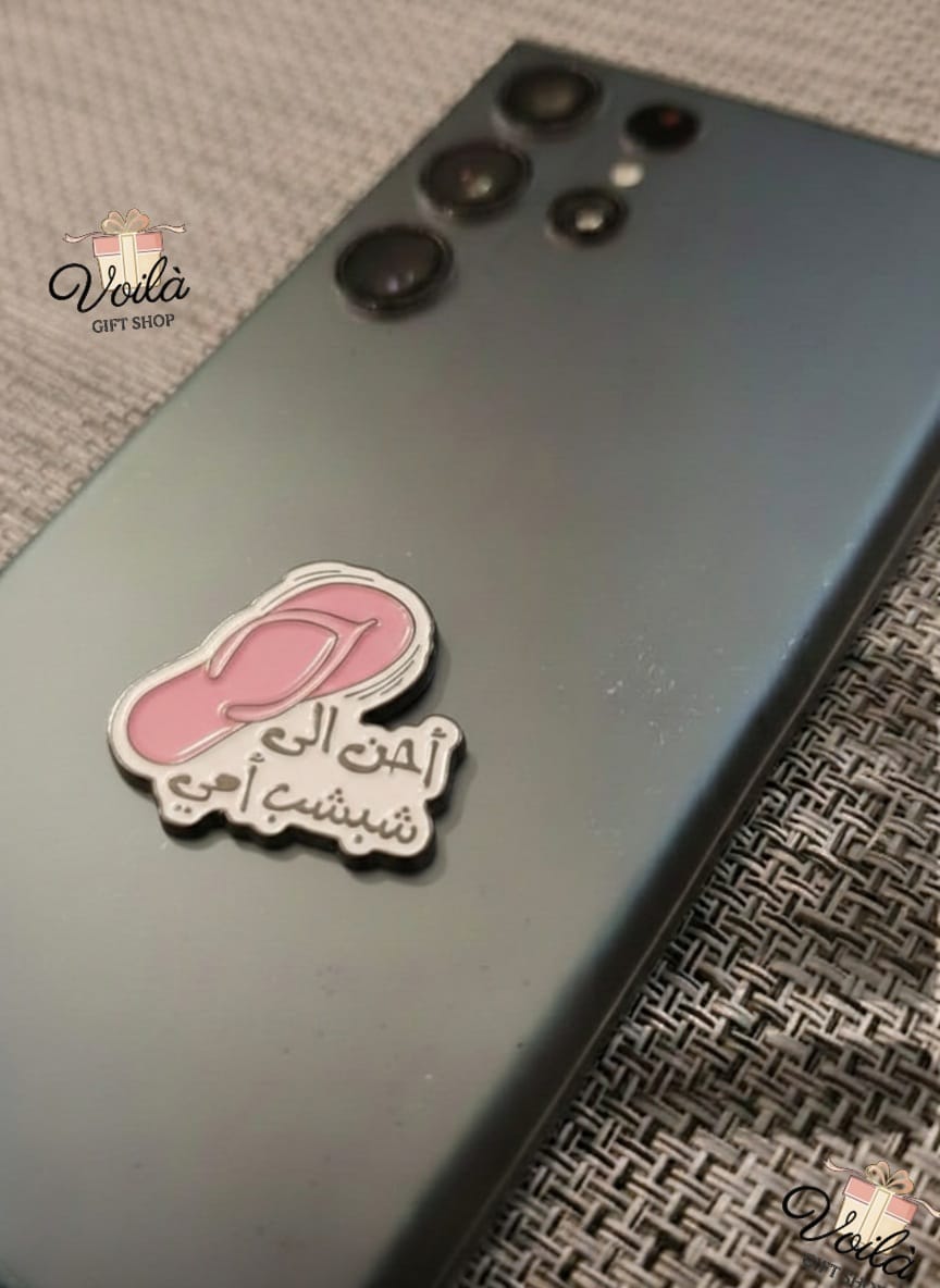 Phone case with a pink footprint design and Arabic text on a textured surface