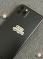 Black smartphone with a coffee-themed sticker on a textured gray surface