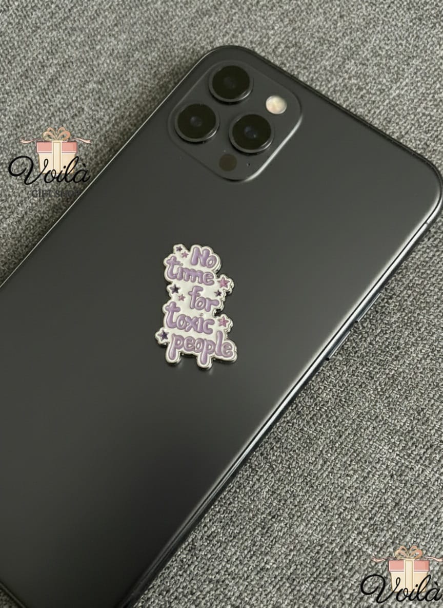 Phone case with 'No time for toxic people' charm on a gray surface